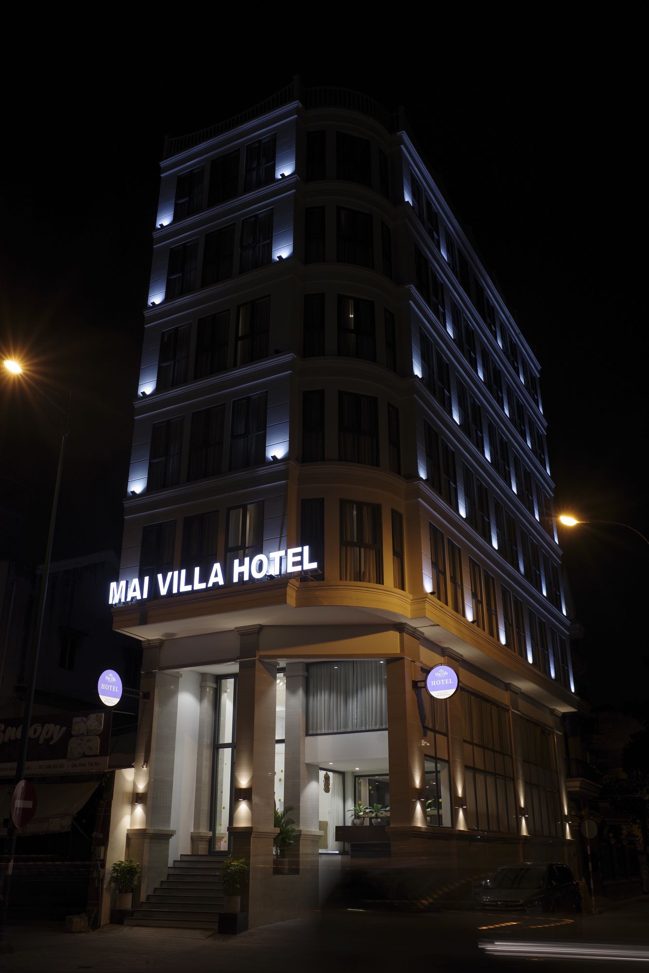 A multi-story hotel with illuminated signage reading 'MAI VILLA HOTEL'.