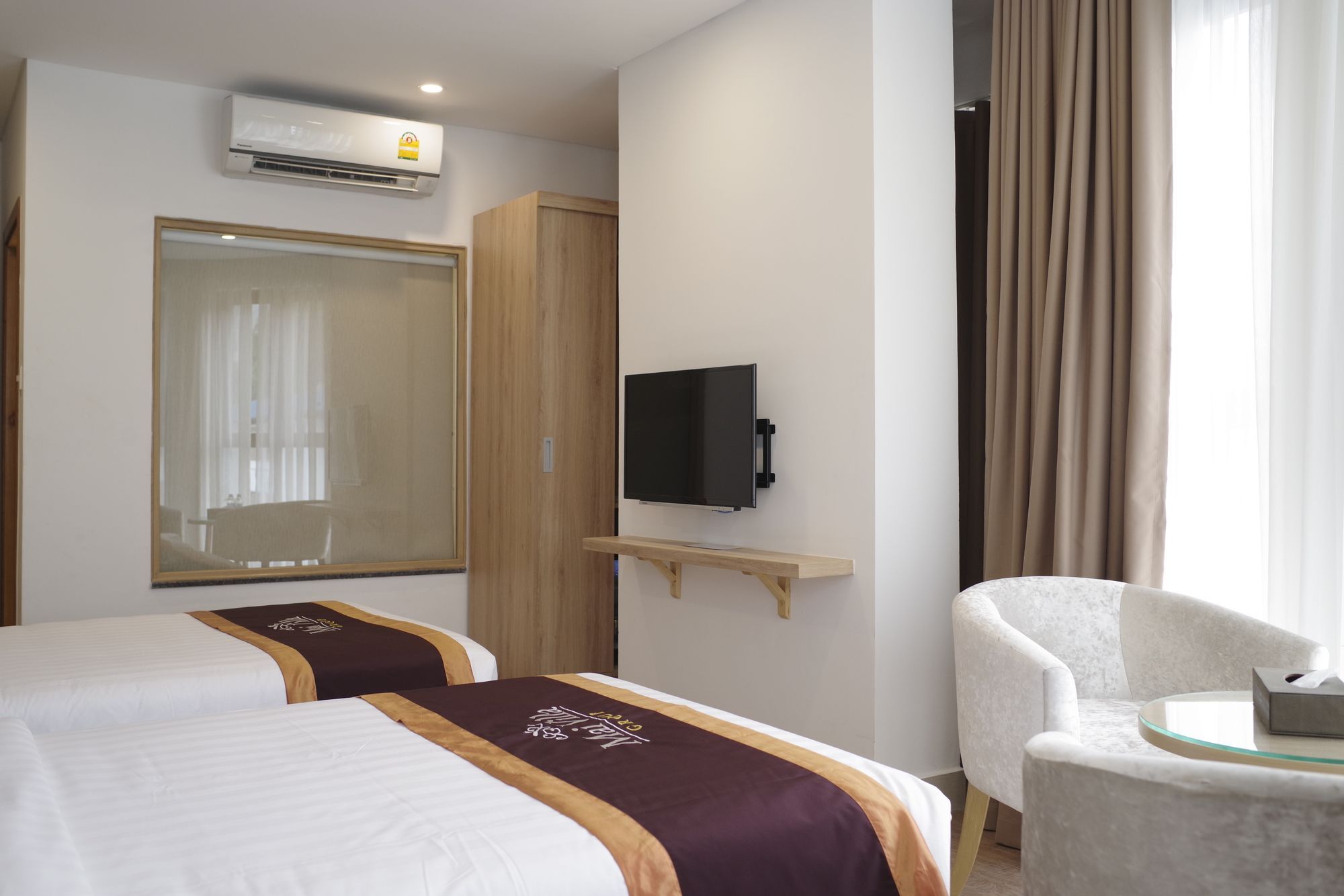 Habitación de hotel con dos camas, un televisor, un armario y una silla.