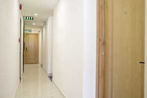 A hallway with two exits, a wooden door, and a marble floor. - My Villa Hotel Airport (Ho Chi Minh City)