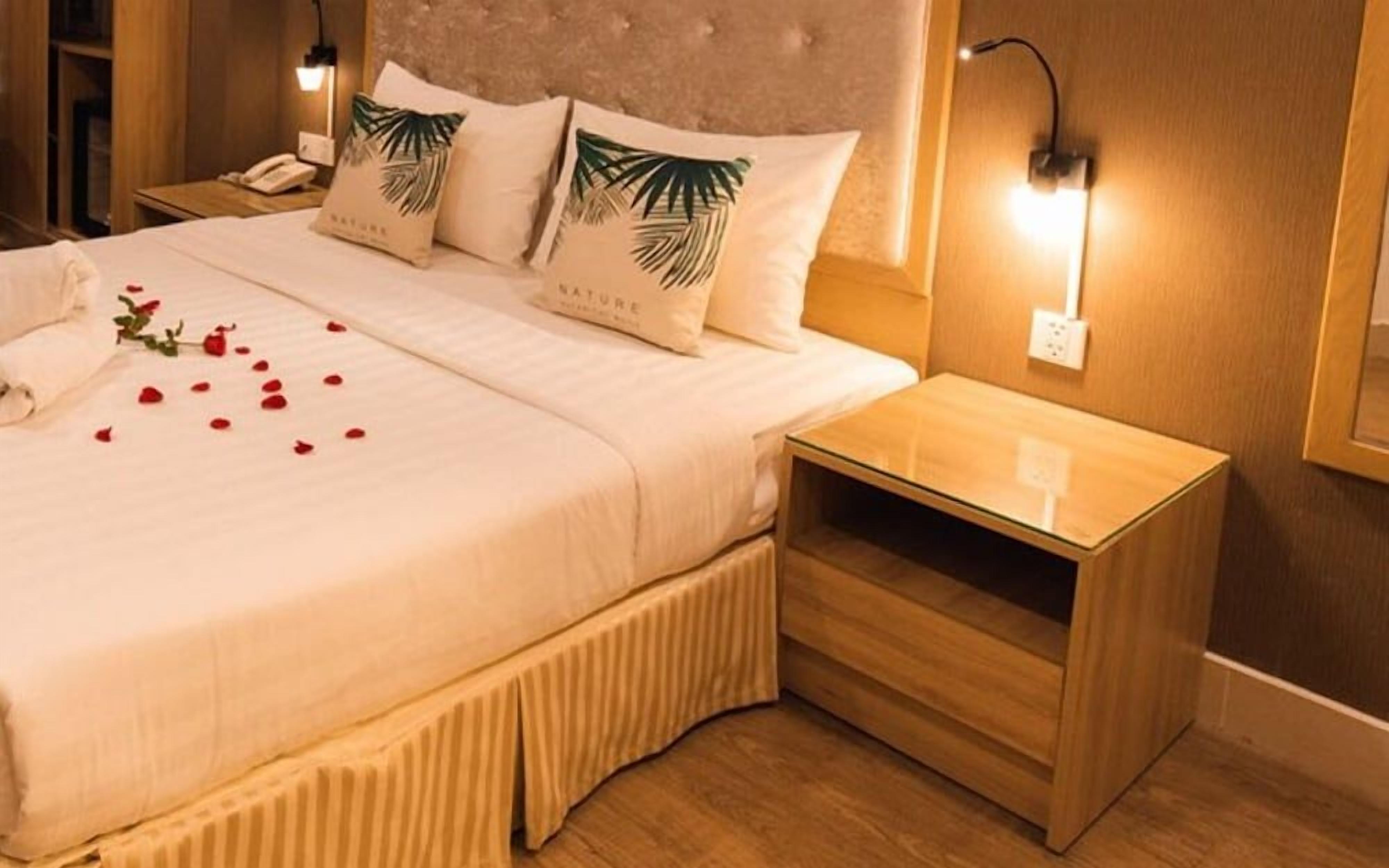 A hotel room with a bed, bedside table, and a nightstand.