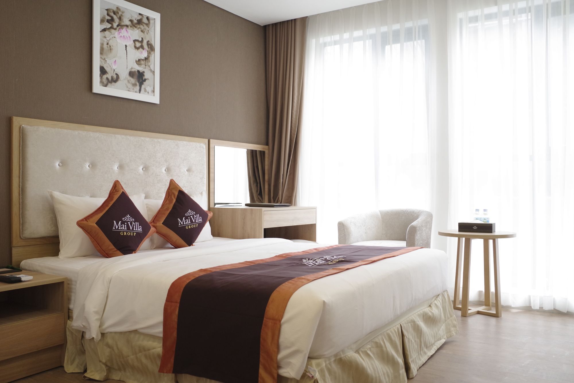 A hotel room with a large bed, a bedside table, a chair, a small table, and a window with curtains.