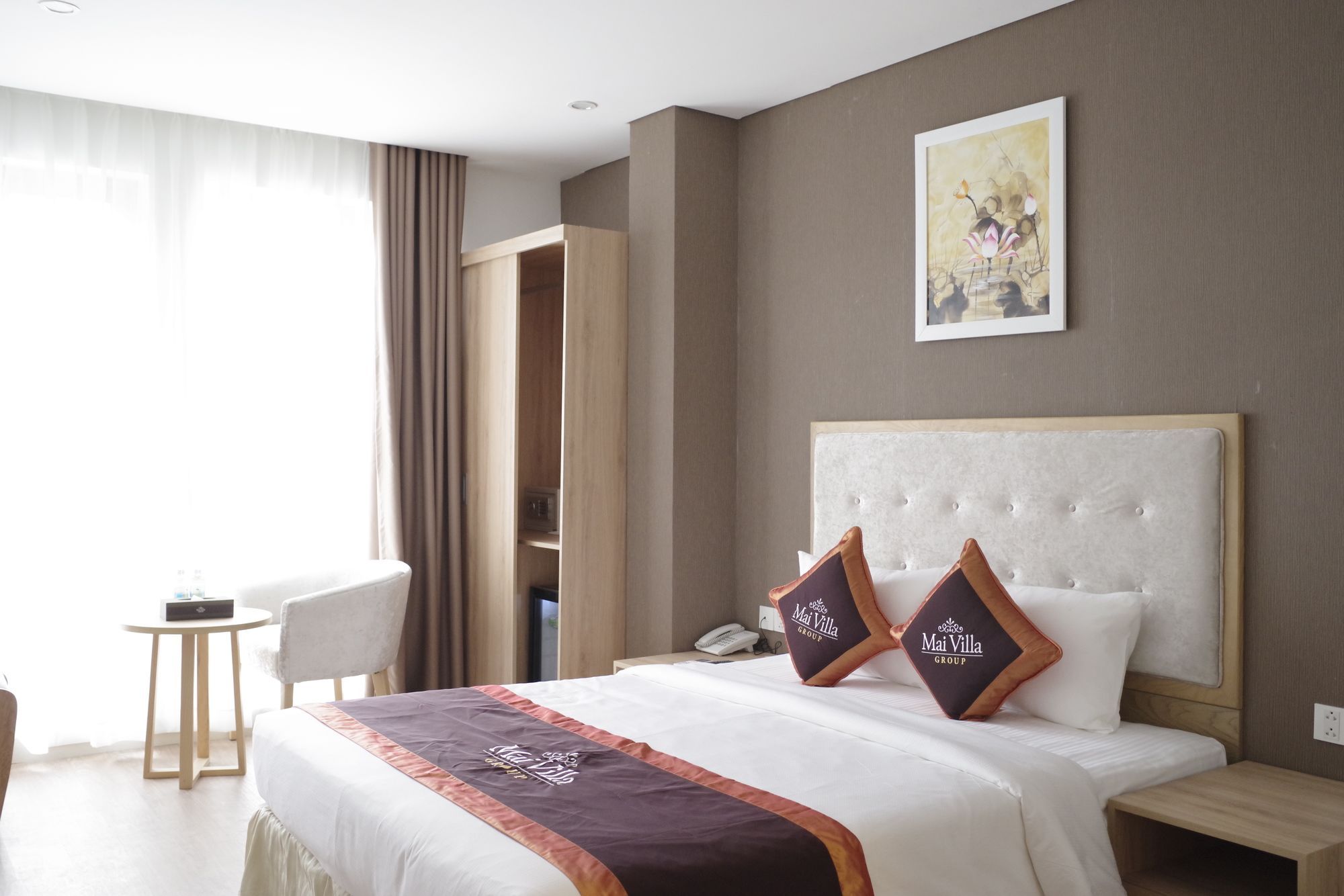 A hotel room with a bed, a bedside table, a chair, a wardrobe, and a painting on the wall.