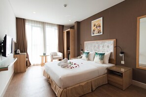 A hotel room with a large bed, a desk with a computer, a chair, and a painting on the wall. - My Villa Hotel Airport (Ho Chi Minh City)