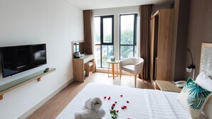 A hotel room with a bed, a TV, a desk with a chair, a window with curtains, and a wardrobe. - My Villa Hotel Airport (Ho Chi Minh City)