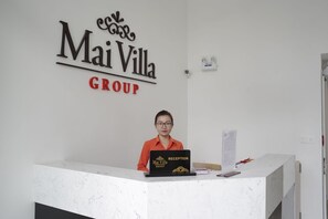 A reception desk with a sign reading 'Mai Villa GROUP' and a person seated behind it. - My Villa Hotel Airport (Ho Chi Minh City)