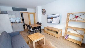 Uma sala de estar moderna com um sofá cinza, mesa de centro de madeira e um espaço de jantar com cadeiras e uma mesa de madeira.