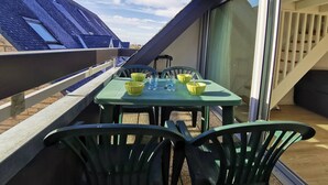 A rooftop terrace with a table and chairs, a glass door leading to a lower level, and a view of the sky. - Carnac cozy T2 with balcony, pets allowed, private parking (Carnac)