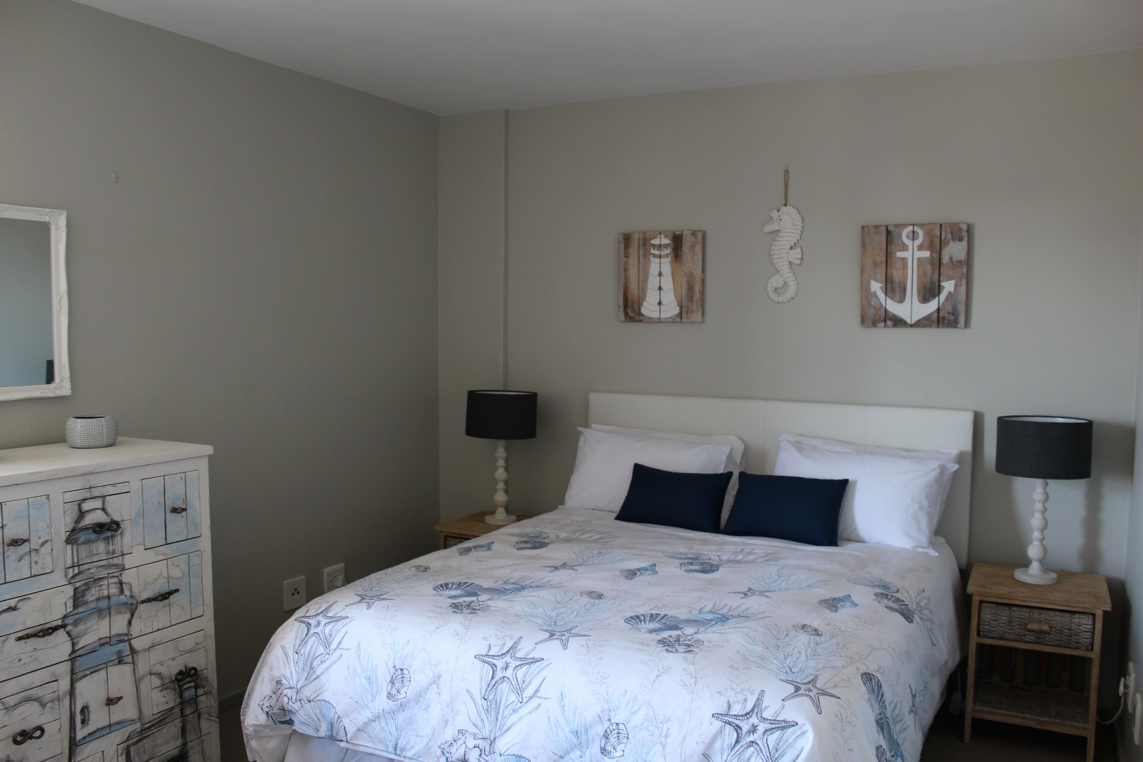 A bedroom with a bed, two bedside tables with lamps, a dresser, and wall art.