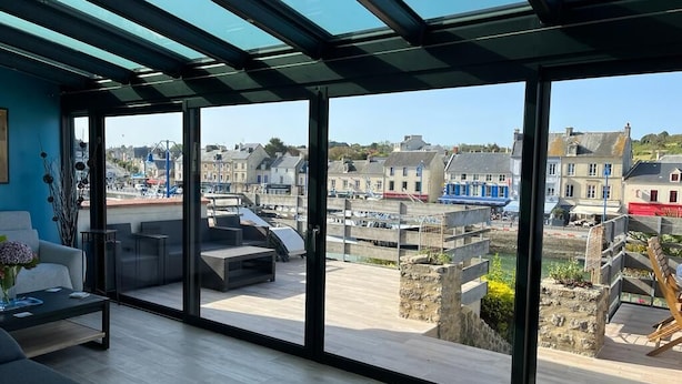 A modern interior with large windows offering a view of a coastal town.