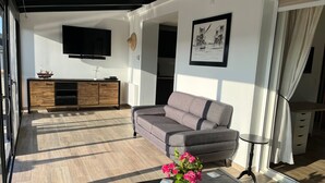 A modern living room with a grey sofa, wooden entertainment unit, and a flat-screen TV.
