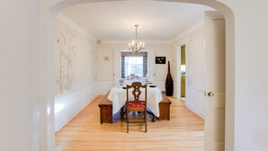 A dining area with a wooden table and chairs, a chandelier, and a view through a window. - The Cottage an urban retreat. (Minneapolis)