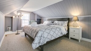 A bedroom with a bed, bedside tables, a floor lamp, and a window. - The Cottage an urban retreat. (Minneapolis)