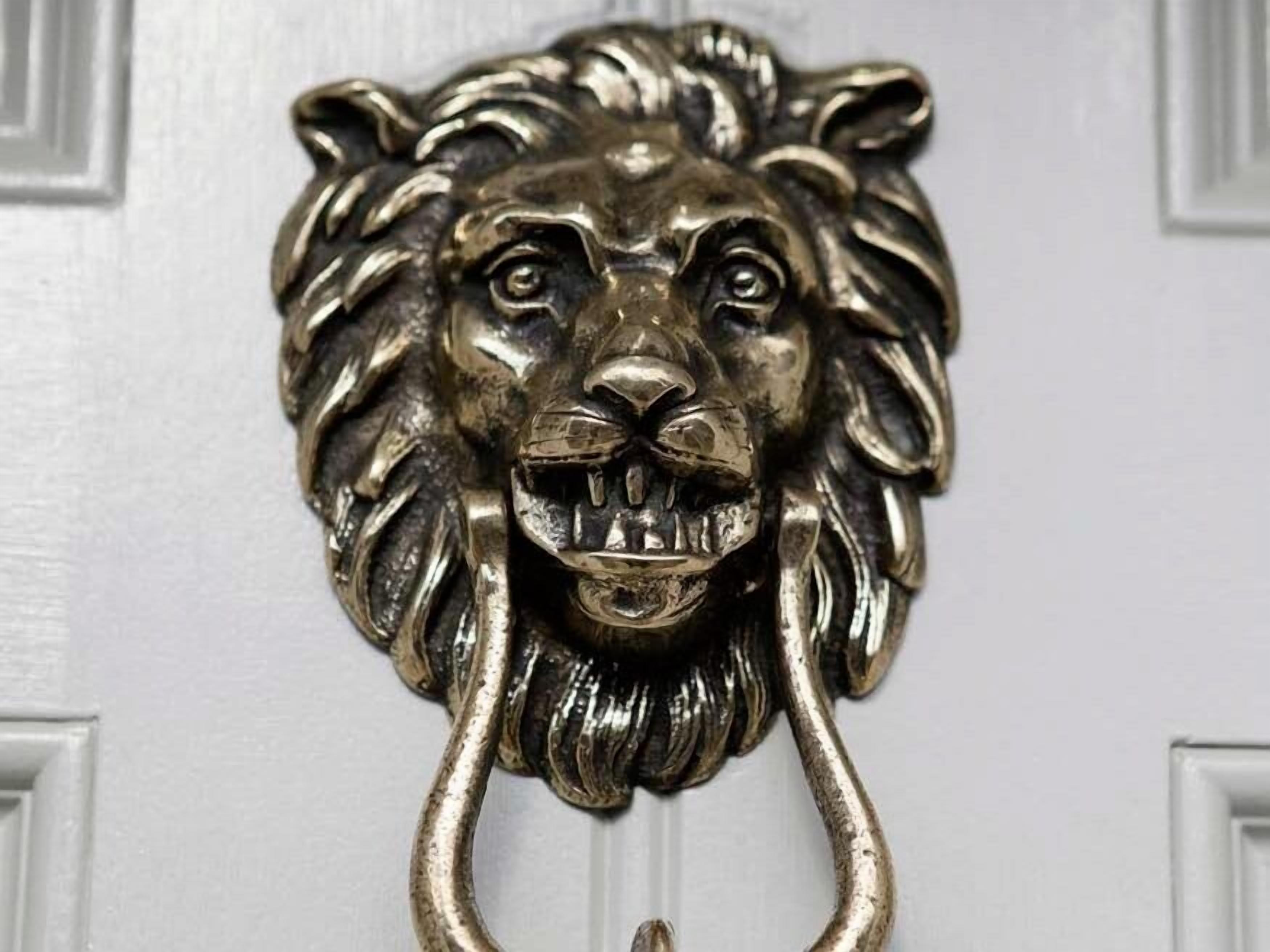 A metallic lion head door knocker with a curved handle.