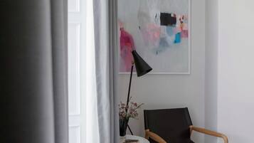 Una stanza con una sedia nera, un tavolino con un vaso di fiori e un quadro appeso al muro.