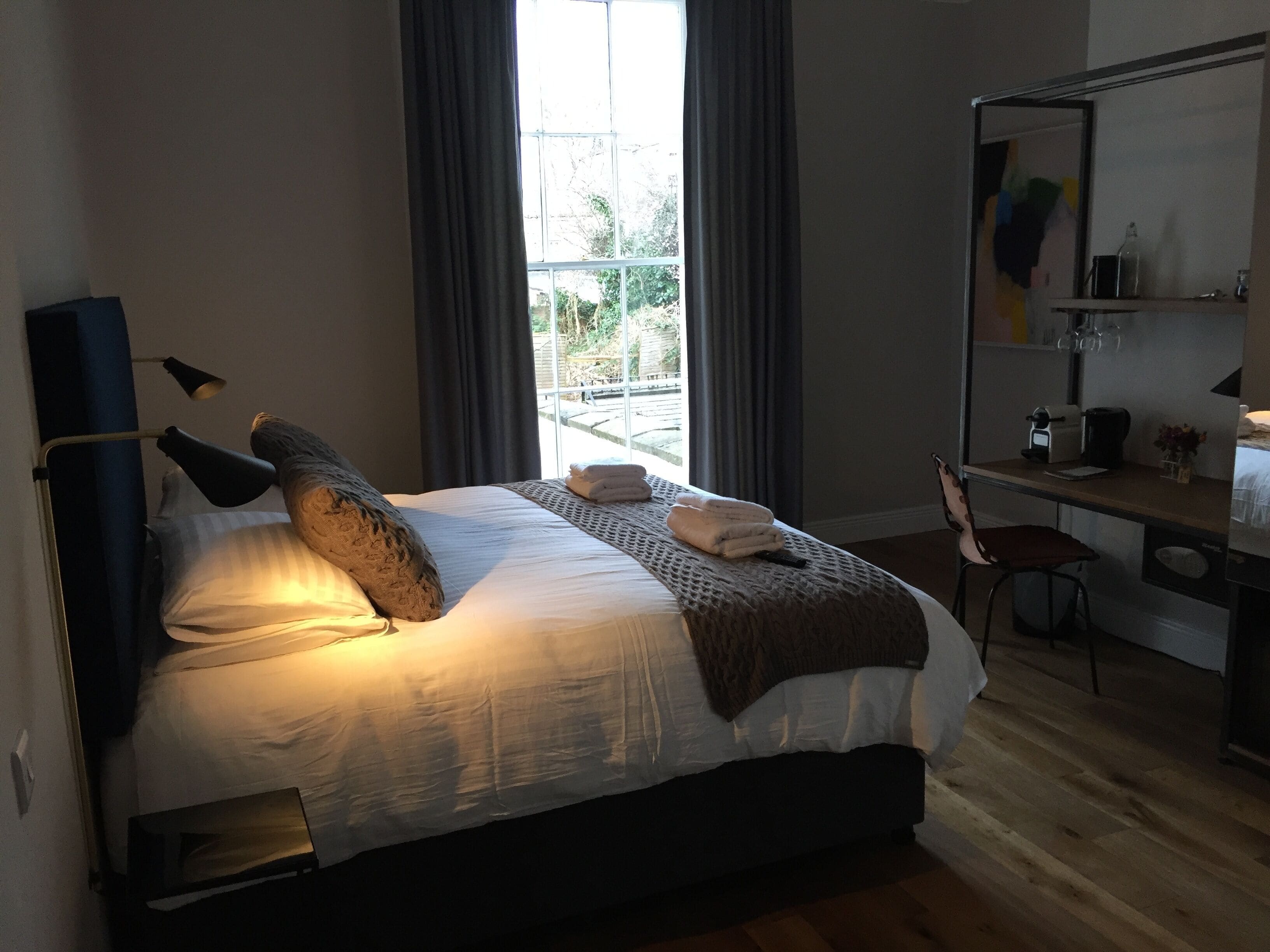 A bedroom with a bed, a desk, a chair, and a large window.