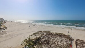 Een strand met een heldere lucht, zandstrand en enkele mensen.
