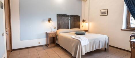 Un dormitorio con cama, mesitas de noche, aire acondicionado de pared y ventana con cortinas.
