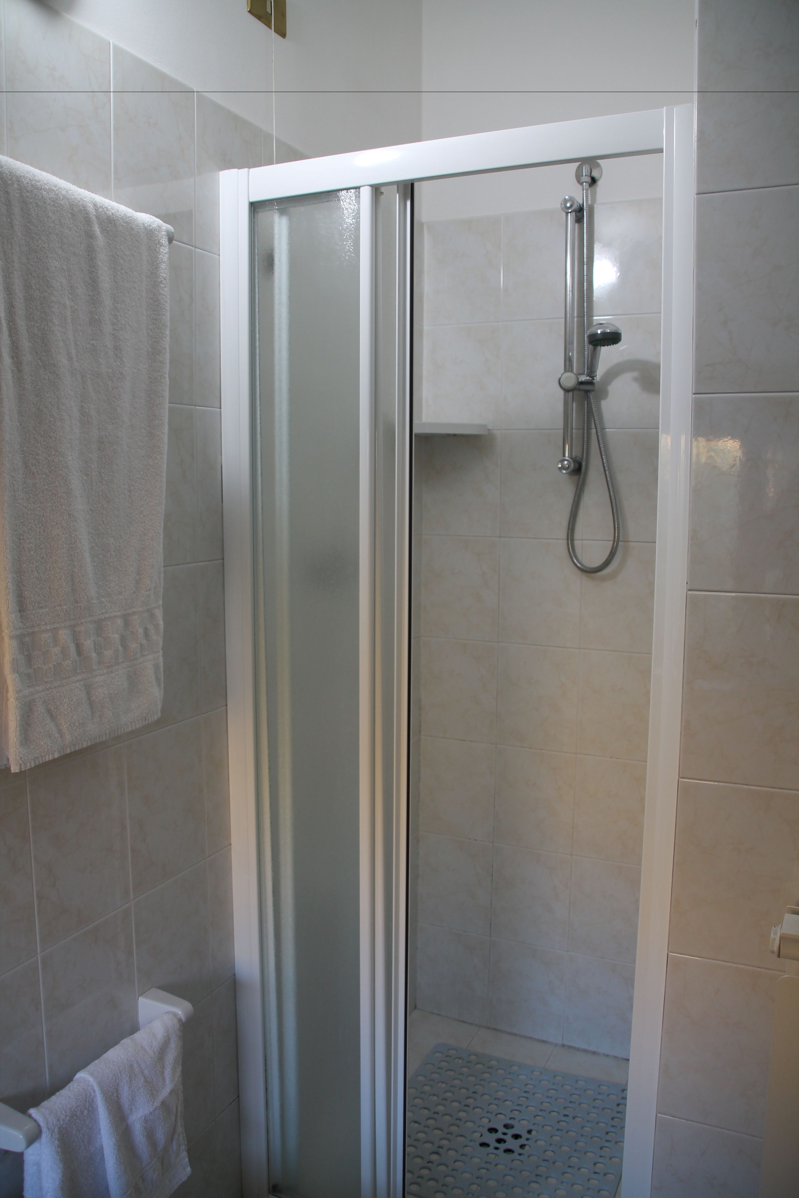 Eine Dusche mit Glastür, Handtuchhalter und Duschkopf.