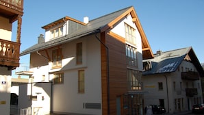 Een gebouw met twee verdiepingen, een witte gevel, houten details en een balkon.