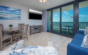 Relax in this spacious living area with a flat-screen TV, dining table, and comfortable sofa, offering a balcony with a view of the sea.