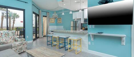 A modern kitchen with a bar area, a dining set, and a sofa.