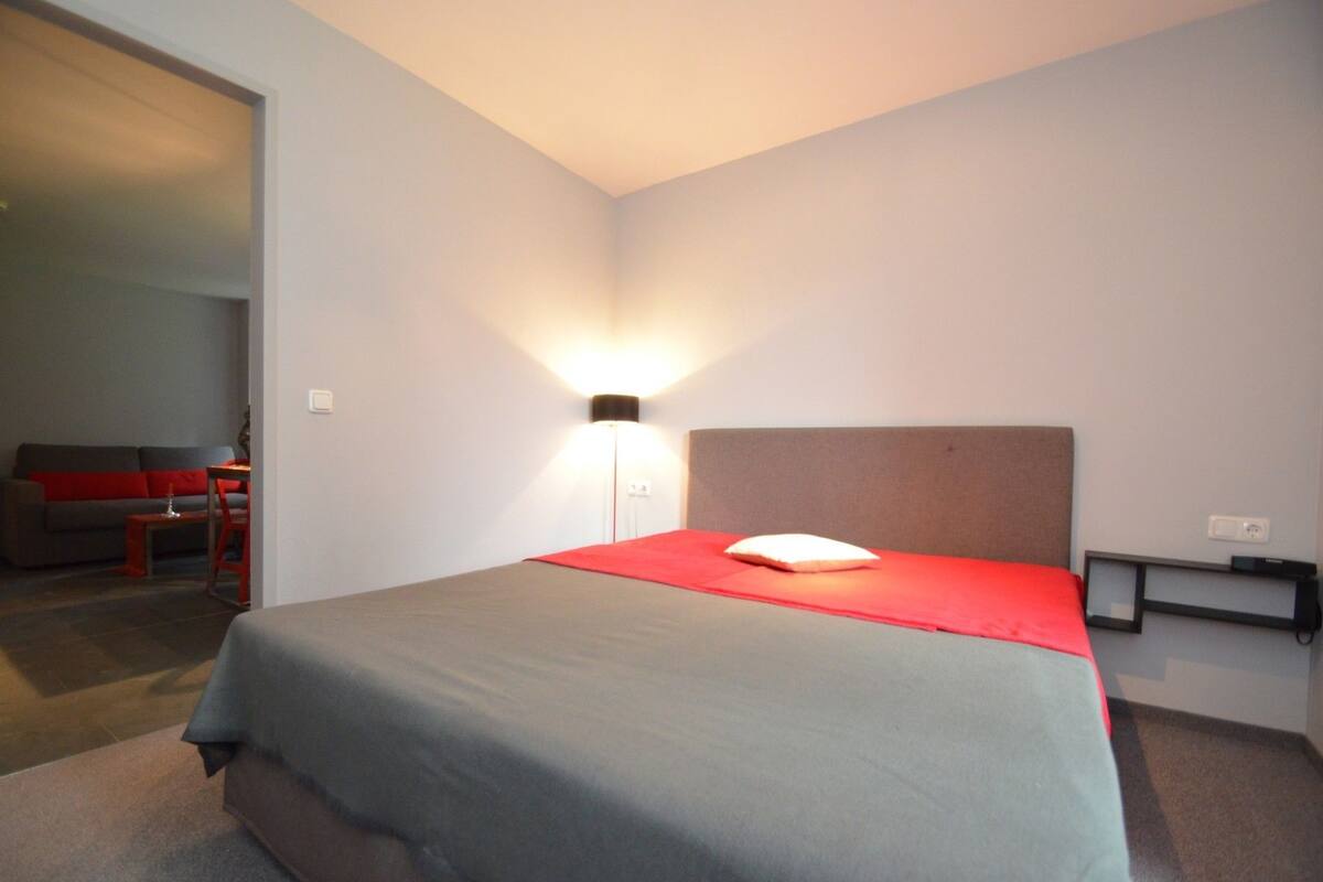 Una habitación de hotel con una cama, una mesita de noche, una lámpara, un sofá y una silla.
