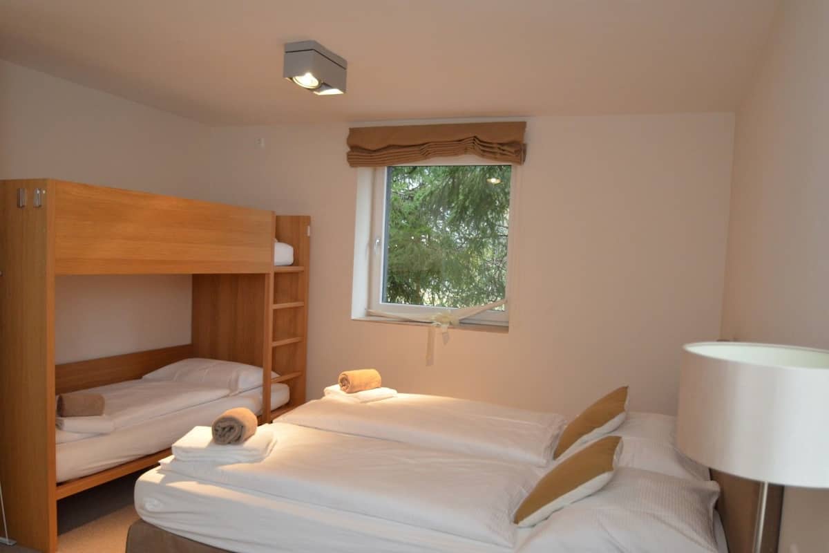 Un dormitorio con literas, una ventana con vistas a árboles y una lámpara de noche.