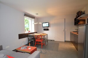 Un espacio habitable compacto con comedor, televisor montado en la pared y kitchenette.
