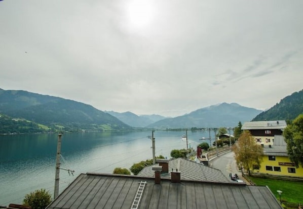 A lakeside view with mountains in the background, a wooden dock, and a yellow building with a sign.