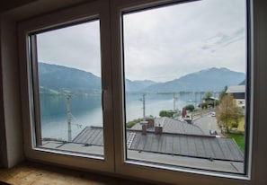 A room with a large window overlooking a lake and mountains.