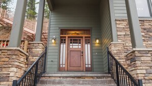 A staircase leading to a wooden door with a stone wall on one side and a metal railing on the other.