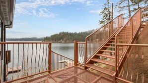 A metal staircase leading to a dock by a lake with a forest in the background.