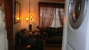 Een wasserette met een wasmachine, een bank en een tafel met een lamp.