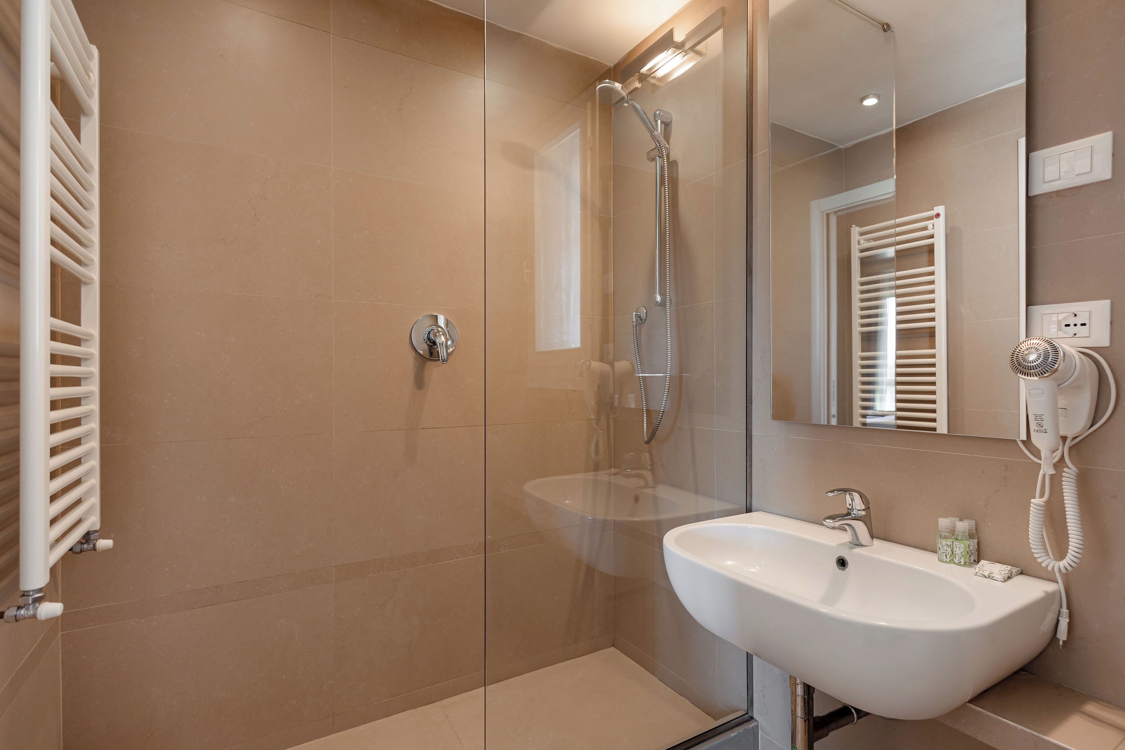 A modern bathroom with a glass-enclosed shower, a white sink, and a mirror reflecting the room.