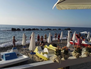Una playa con varios barcos y sombrillas, algunas decoradas con flores.
