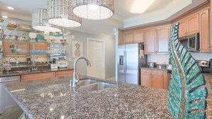A kitchen with granite countertops, stainless steel appliances, wooden cabinets, and decorative glassware. - Phoenix West ~ 8th FLOOR! ~ Condo 802 ~ 3BR 4 BA (Orange Beach)