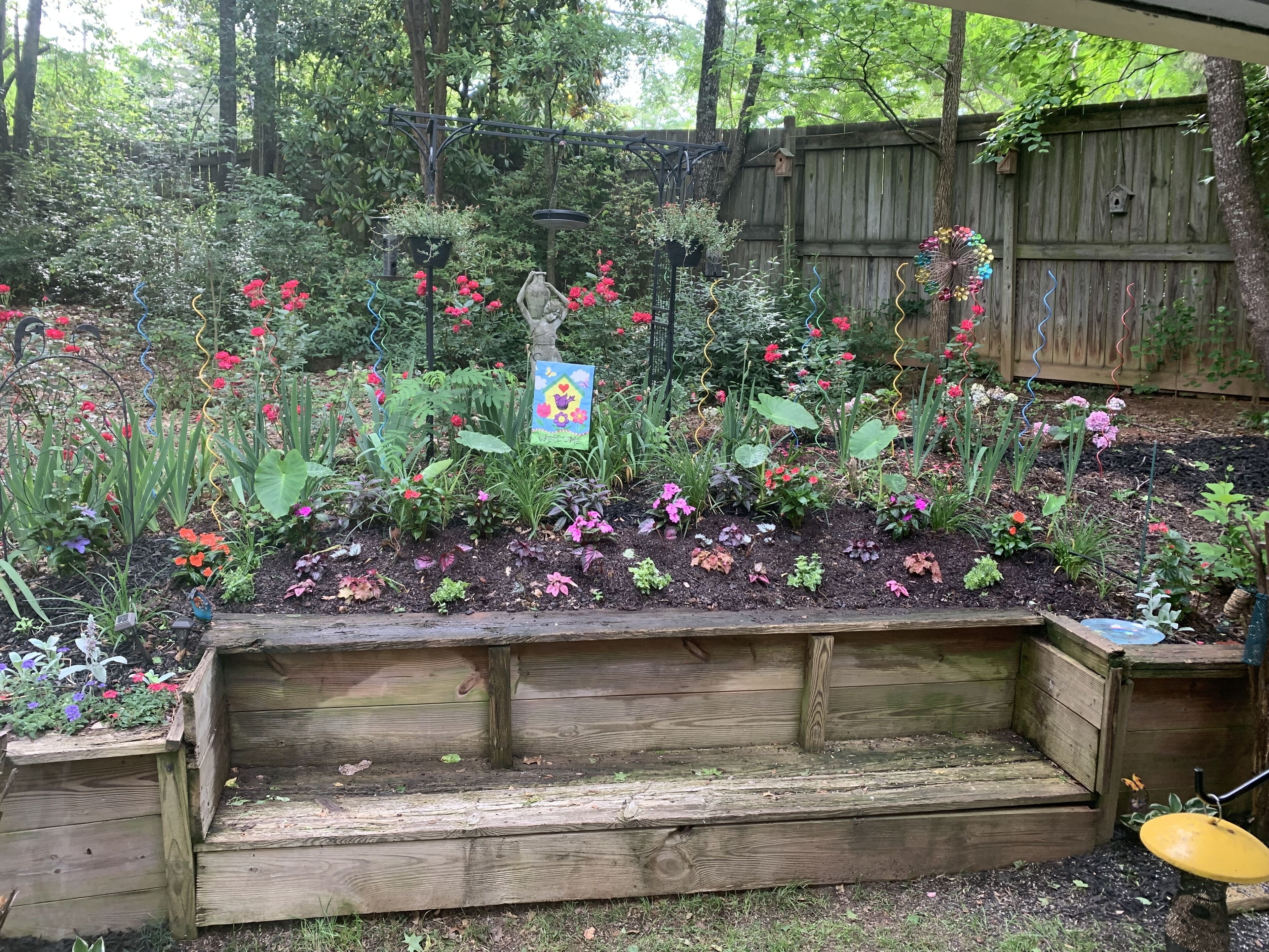 A garden with raised beds, wooden structures, and various plants.