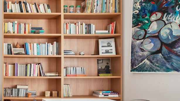 A modern library with wooden bookshelves filled with books, a white table, and chairs. - Appartamento moderno alla Cala by Wonderful Italy (Palermo)
