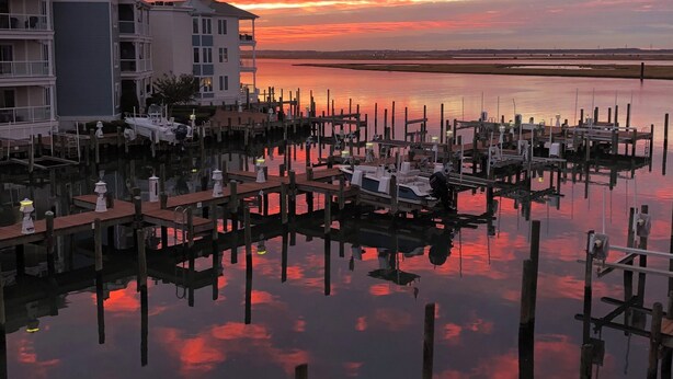 A marina with docked boats and a sunset over a calm body of water.