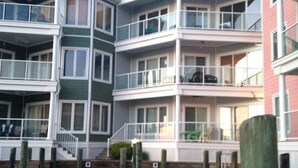 A multi-story waterfront building with balconies and a dock.
