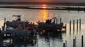 A sunset over a calm body of water with boats docked at a pier.