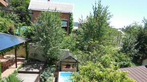 A backyard with a swimming pool, a patio with outdoor furniture, and a house with a tiled roof.