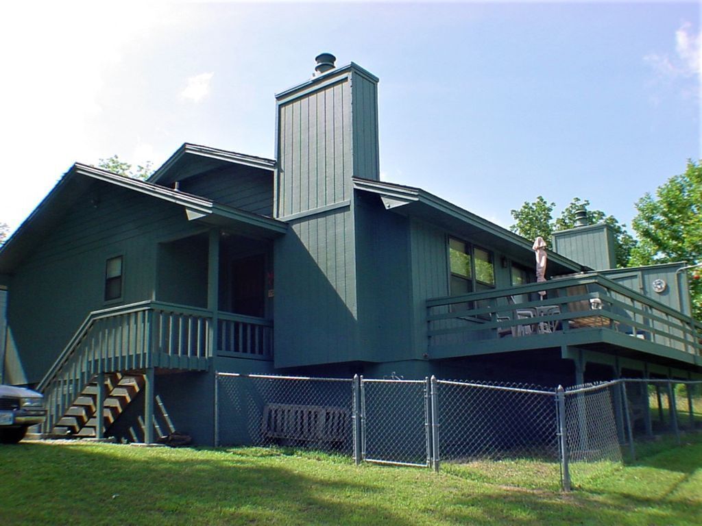 A two-story house with a covered porch and a small staircase leading to the upper level.