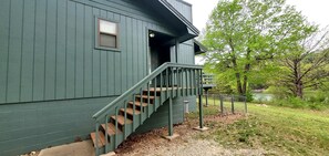 Un edificio de madera verde con una escalera que lleva a un porche.