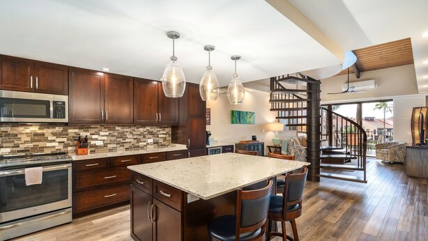 A modern kitchen with a central island, wooden cabinets, and a stainless steel oven. - Kamaole Sands 3-406 - Modern Kitchen, Large Lanai, Enclosed Private MB, Split AC (Kihei)