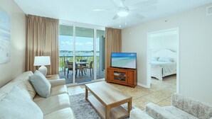 Een woonkamer met een bank, salontafel, televisie en een balkon met uitzicht.