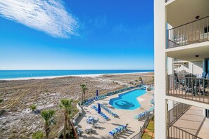 A hotel with a pool, beach view, and outdoor seating.