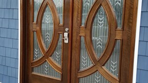 Een houten dubbele deur met ingewikkelde glasdecoraties en een sleutelgat.