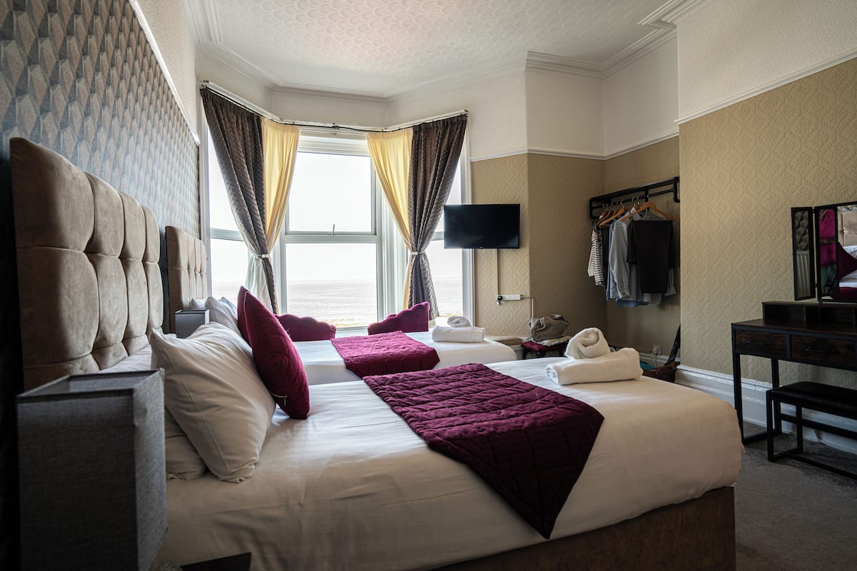 A hotel room with two beds, a flat-screen TV, a desk, and a wardrobe.