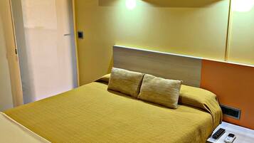 Een hotelkamer met een bed, een nachtkastje met een telefoon en een bedlampje.